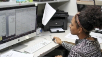 A female researcher sitting at a computer imputing data.