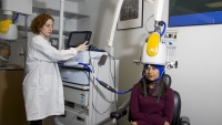 A physician performing a brain scan on a patient in an exam room.