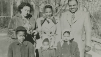 A black and white photo of an African American family standing outside in winter coats.