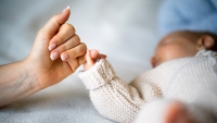Close-up of mother's hand holding newborn baby's hand