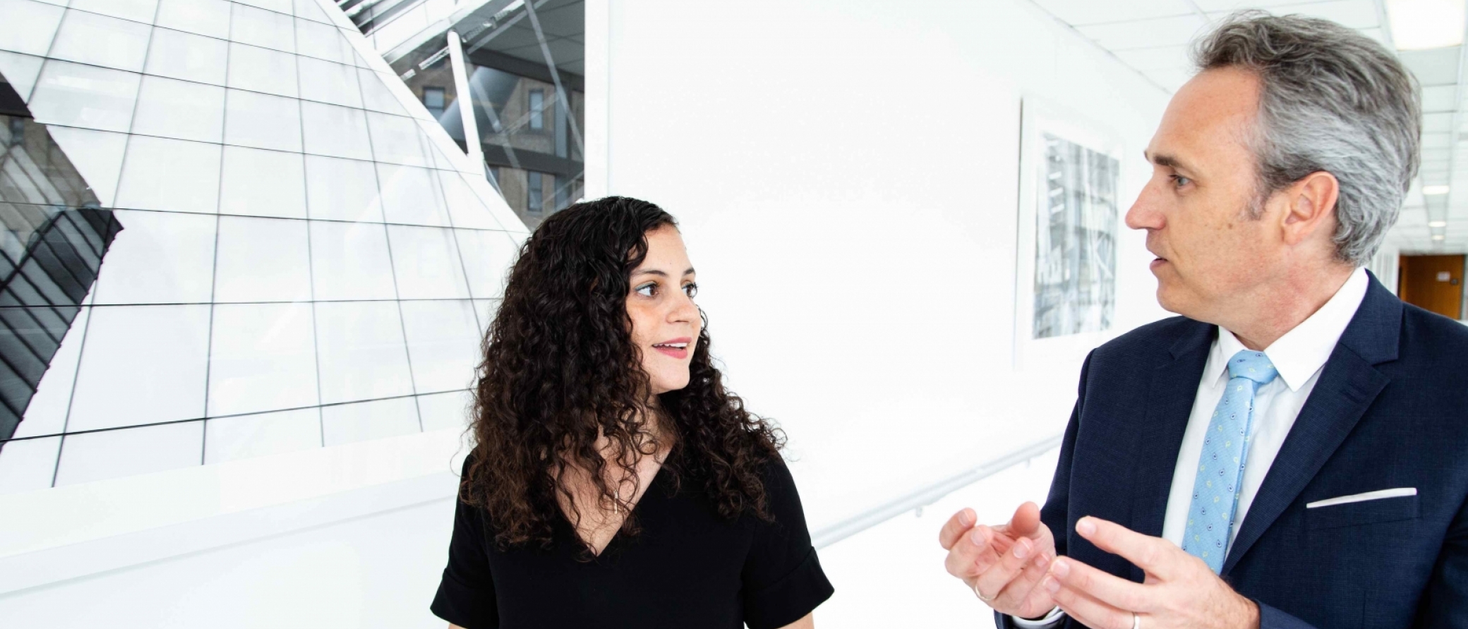A woman and man walk down a hallway together.